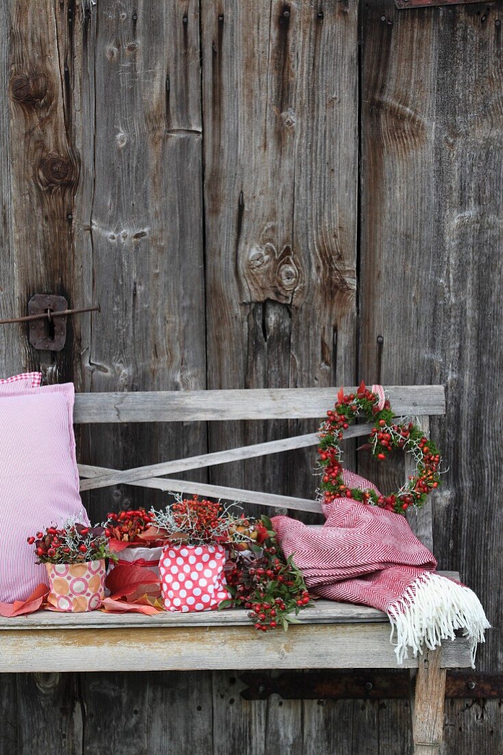 Autumnal flower arrangements and romantic door wreath arranged on rustic wooden bench against board wall