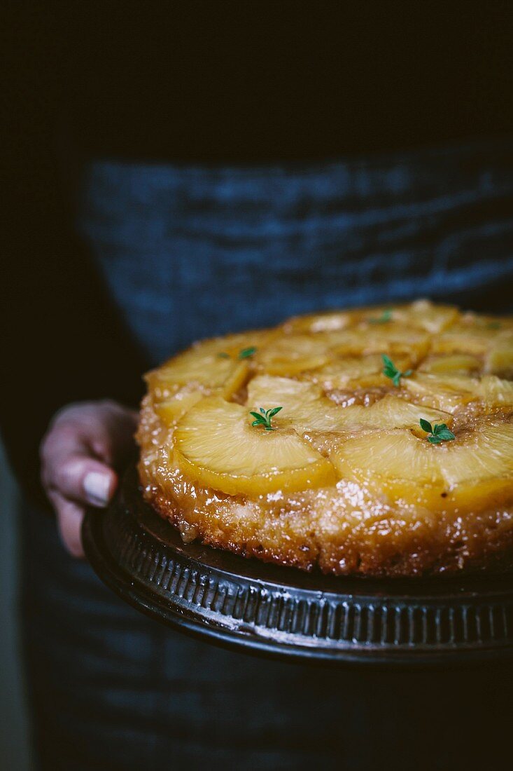 A woman holding a pineapple upside down cake