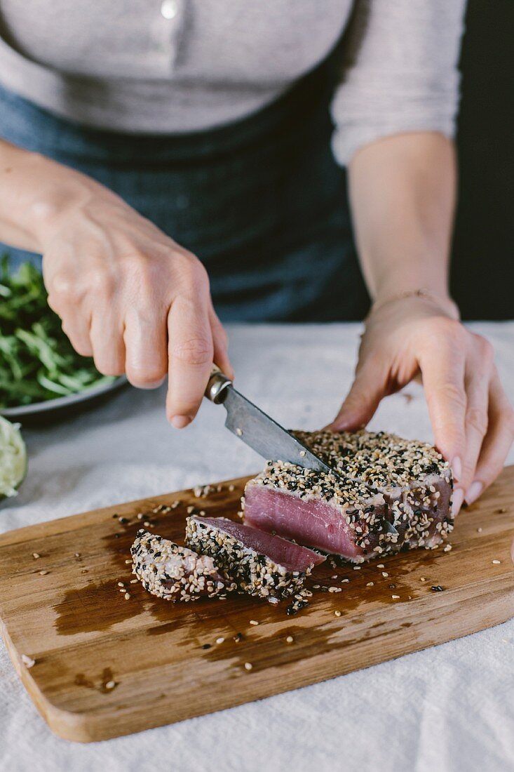 A woman is slicing a sesame crusted and seared yellow fin tuna