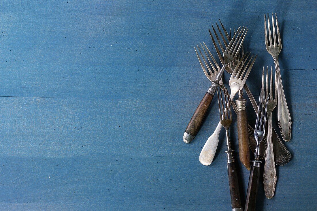Set of vintage forks over blue wooden surface