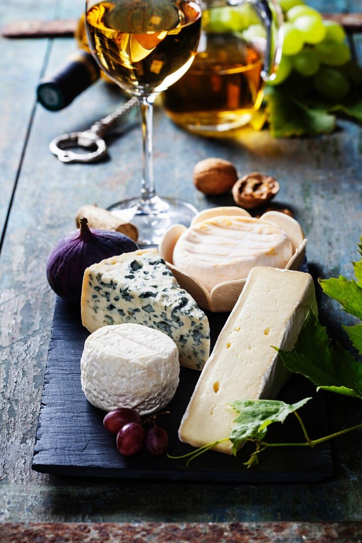 Various types of cheese and white wine on wooden background