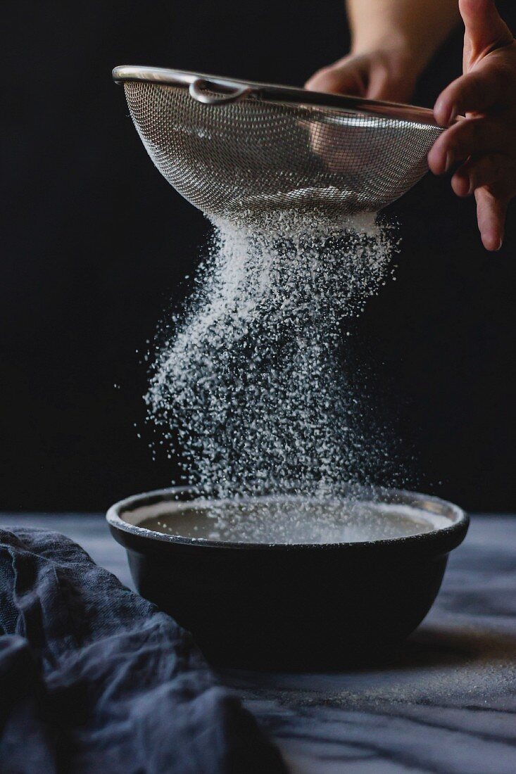 Sifting flour into a bowl whilst cooking
