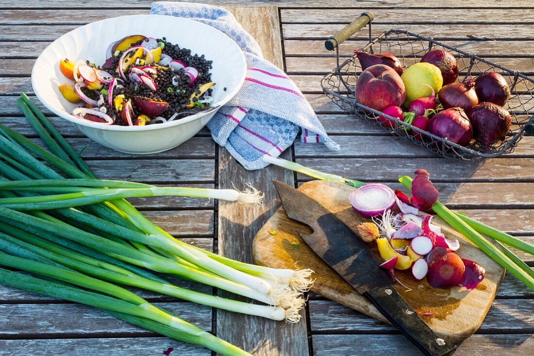 Zutaten für Linsensalat mit Obst auf einem hölzernen Gartentisch