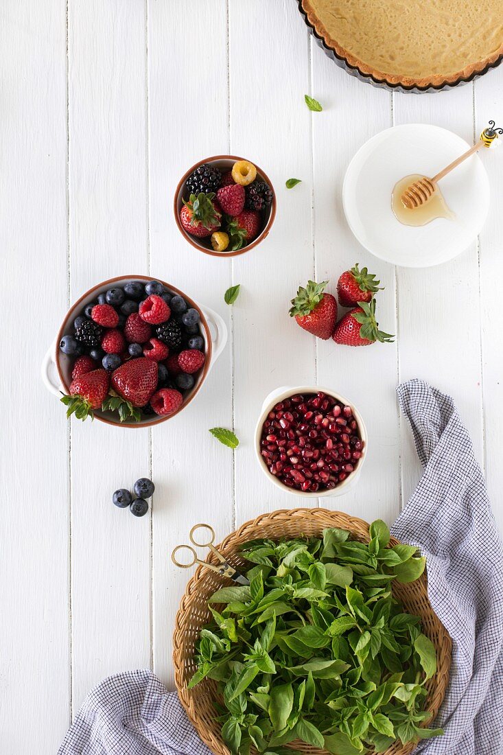 Zutaten für Törtchen mit Sommerbeeren auf weißem Holzuntergrund