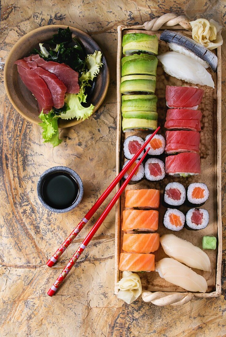 Sushi-Set mit Nigiri, Sashimi und Sushiröllchen serviert mit Stäbchen und Sojasauce