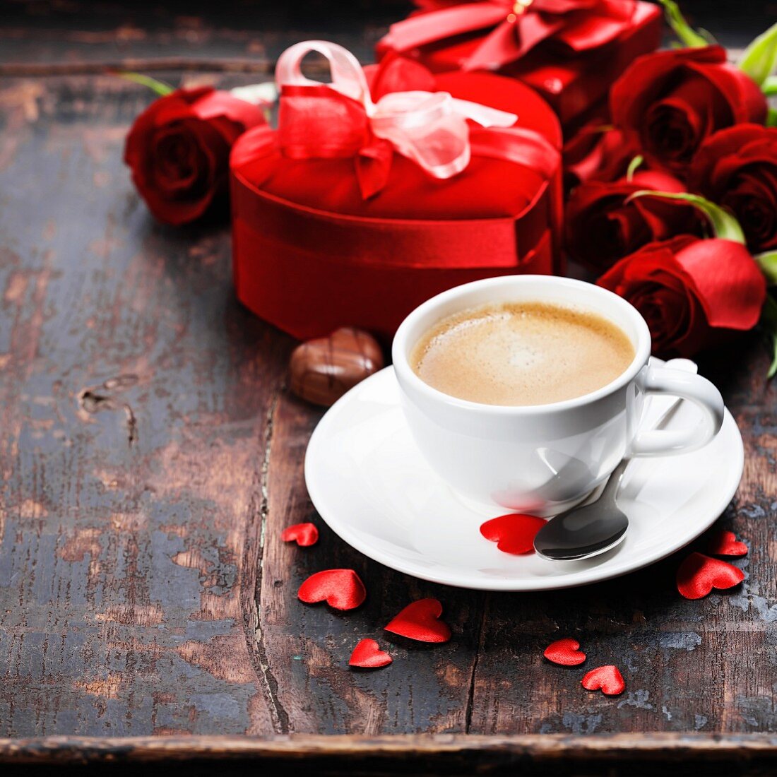 Valentinstag: Tasse Kaffee, Rosen und Geschenkbox auf Holzuntergrund