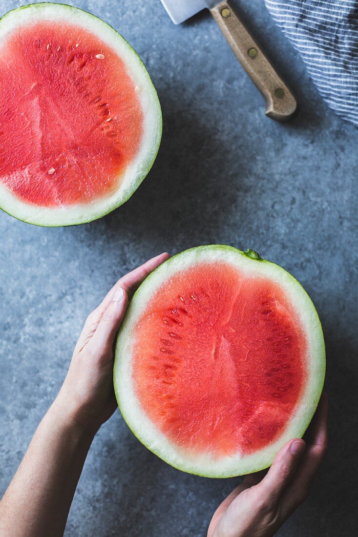 Hände halten halbierte Wassermelone (Aufsicht)