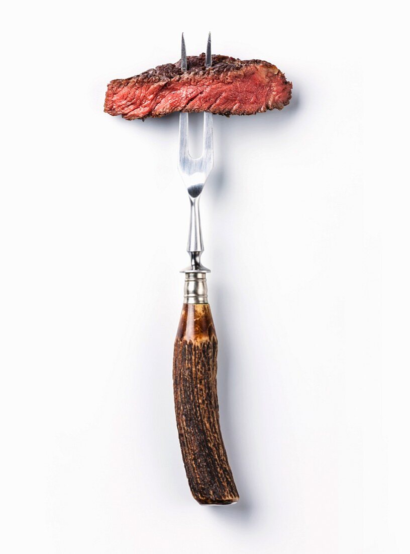 Sliced beef steak ribeye on meat fork on white background
