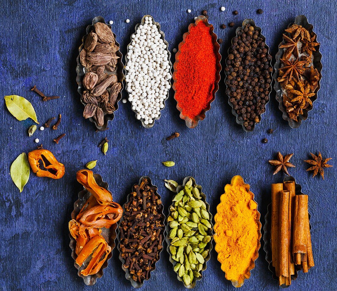 Cardamom, Star anise, Peppers, Bay Leaf, Cinnamon, Clove, Mace and Black Cardamom on a rustic background