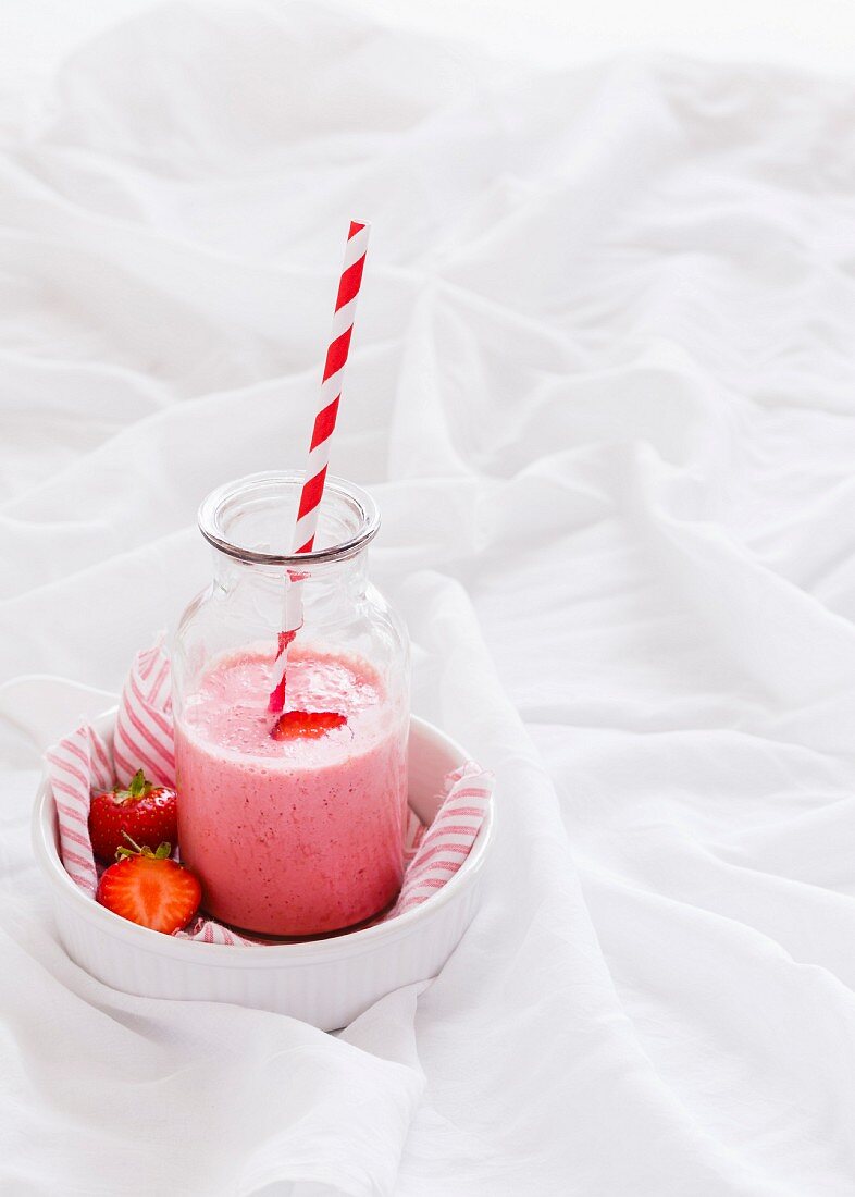 Erdbeersmoothie in einer Glasflasche mit Strohhalm