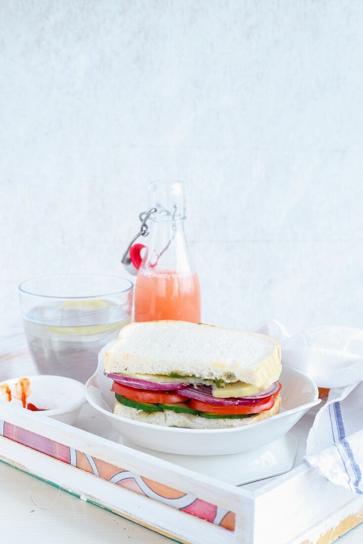 Vegetarisches Mumbai Sandwich serviert mit Saft auf weißem Tablett