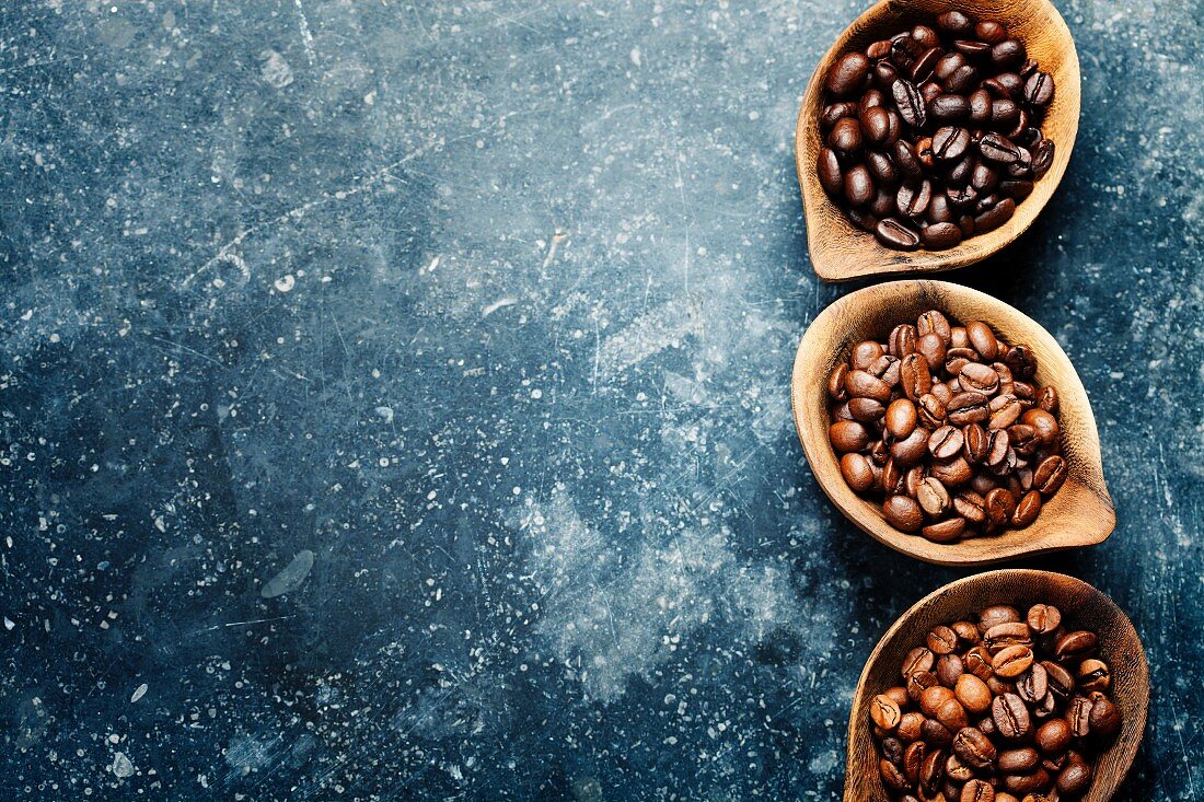 Drei verschiedene Sorten Kaffeebohnen auf dunklem Vintage-Untergrund