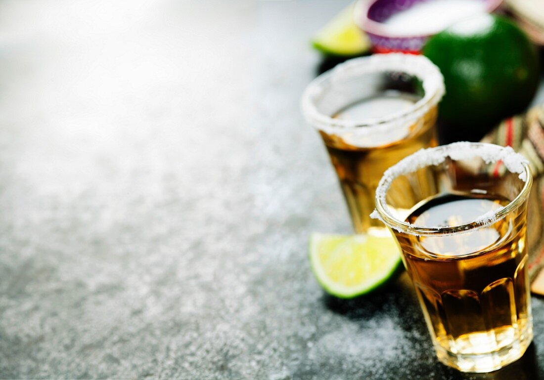 Tequila shots with lime and salt on rustic background