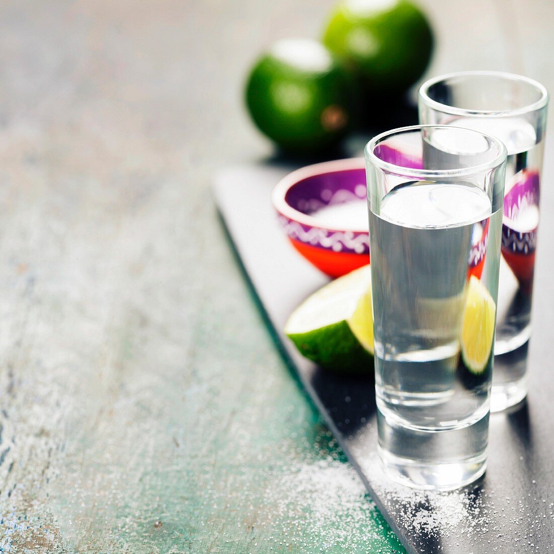 Tequila mit Limette und Salz vor rustikalem Hintergrund