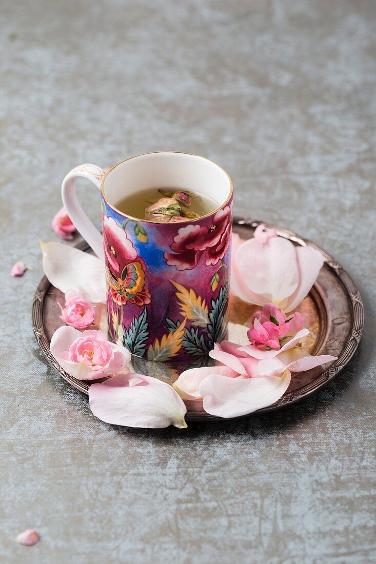 Rose blossom tea and rose petals on a silver plate