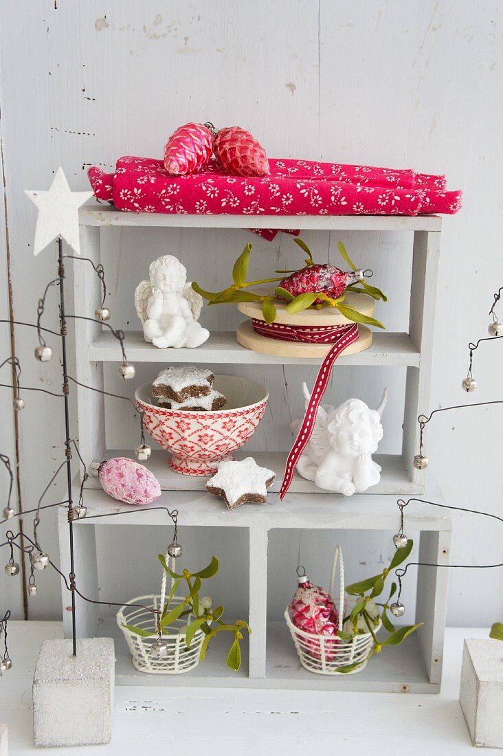 Shelves festively decorated with angels. biscuits, glass ornaments and mistletoe