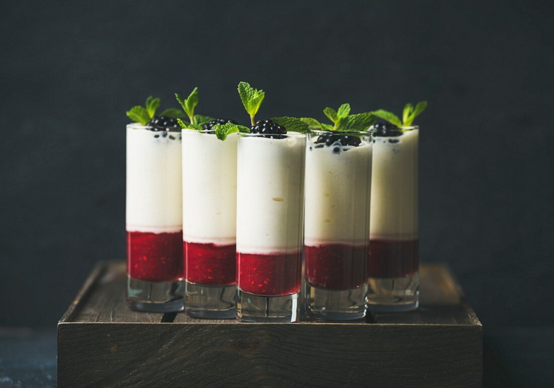 Dessert in glass with blackberries and mint leaves over dark background