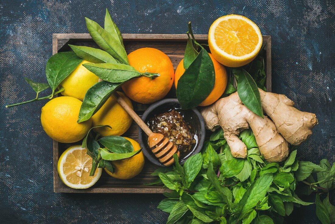 Ingredients for making immunity boosting natural drink: Lemons, oranges, mint, ginger, honey in wooden box