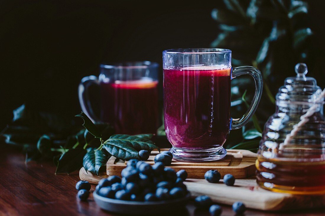 A glass of blueberry hot toddy garnished with a lemon slice
