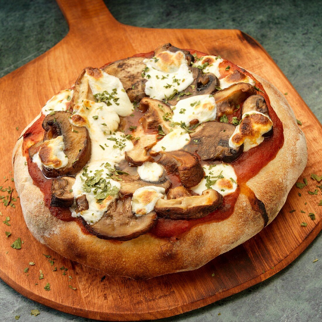 Ganze Vollkorn Pizza mit Pilzen und Mozzarella auf Pizzaschieber