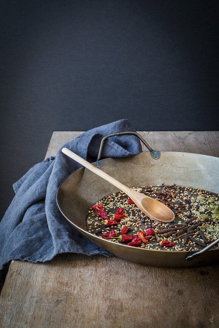 Whole spices prepared for roasting in a pan on wooden table