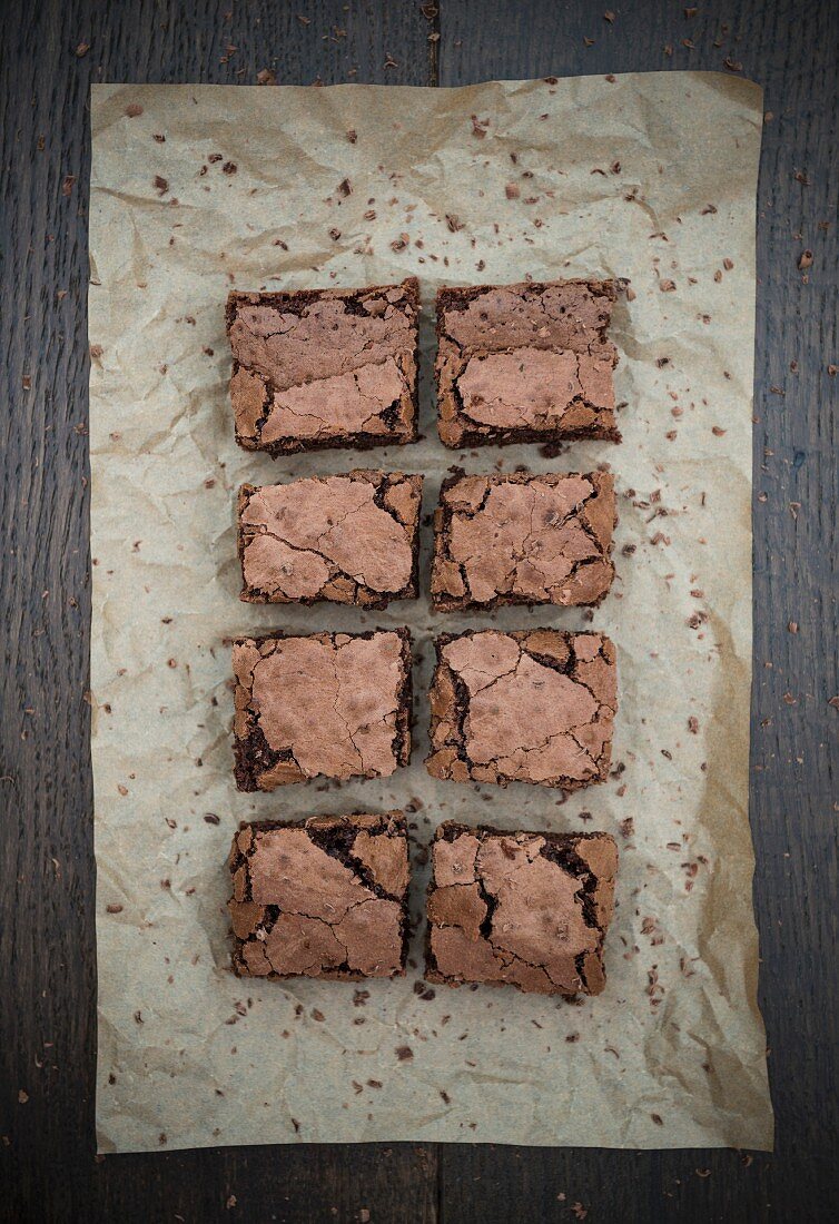 Schokoladen-Brownies in Stücken auf Backpapier (Aufsicht)