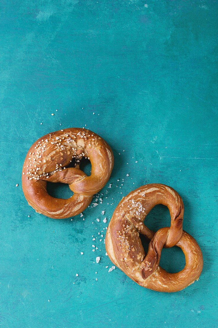 Traditional beer snack salted pretzels with sea salt and sesame seeds over old turquoise wooden background