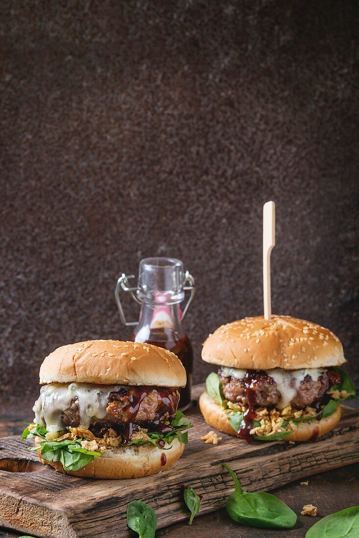 Two hamburgers with beef burger cutlet, fried onion, spinach, ketchup sauce and blue cheese in traditional buns