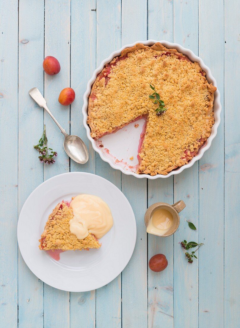 Plum pie with a crumble topping on a blue board