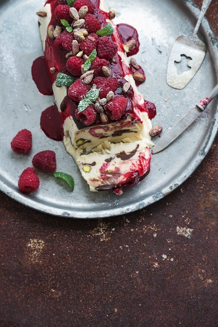 Semifreddo or italian cheese ice-cream dessert with garden berries and mint on vintage silver tray