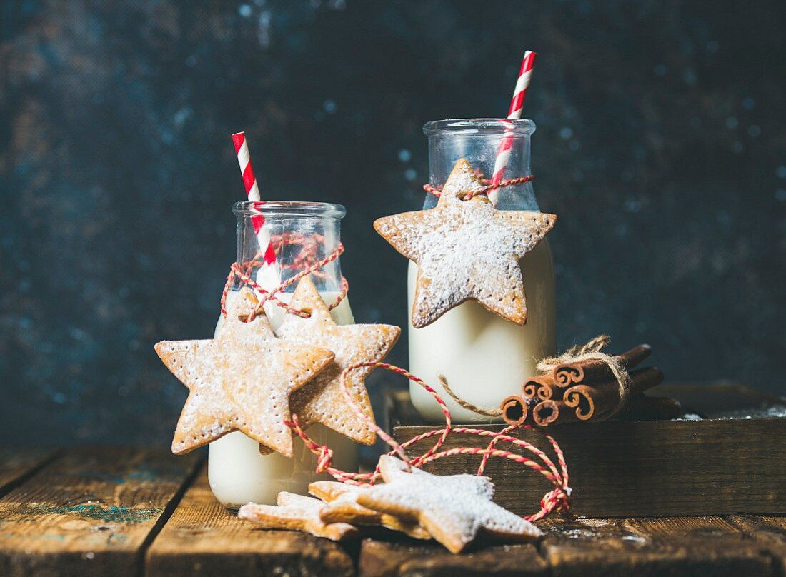 Milch in Glasflaschen weihnachtlich dekoriert mit sternförmigen Lebkuchen