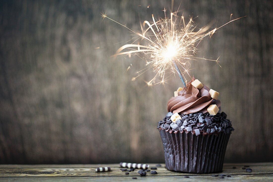 Schokoladen-Cupcake mit brennender Wunderkerze