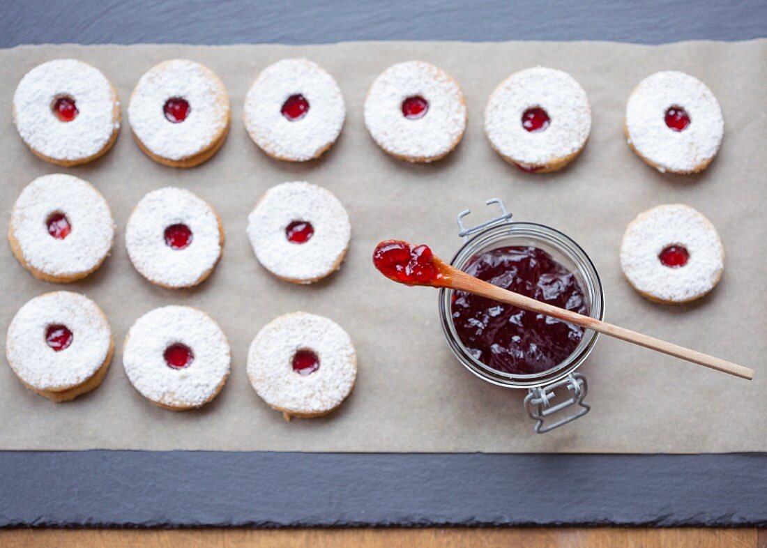 Spitzbuben Plätzchen auf Backpapier und Marmeladenglas