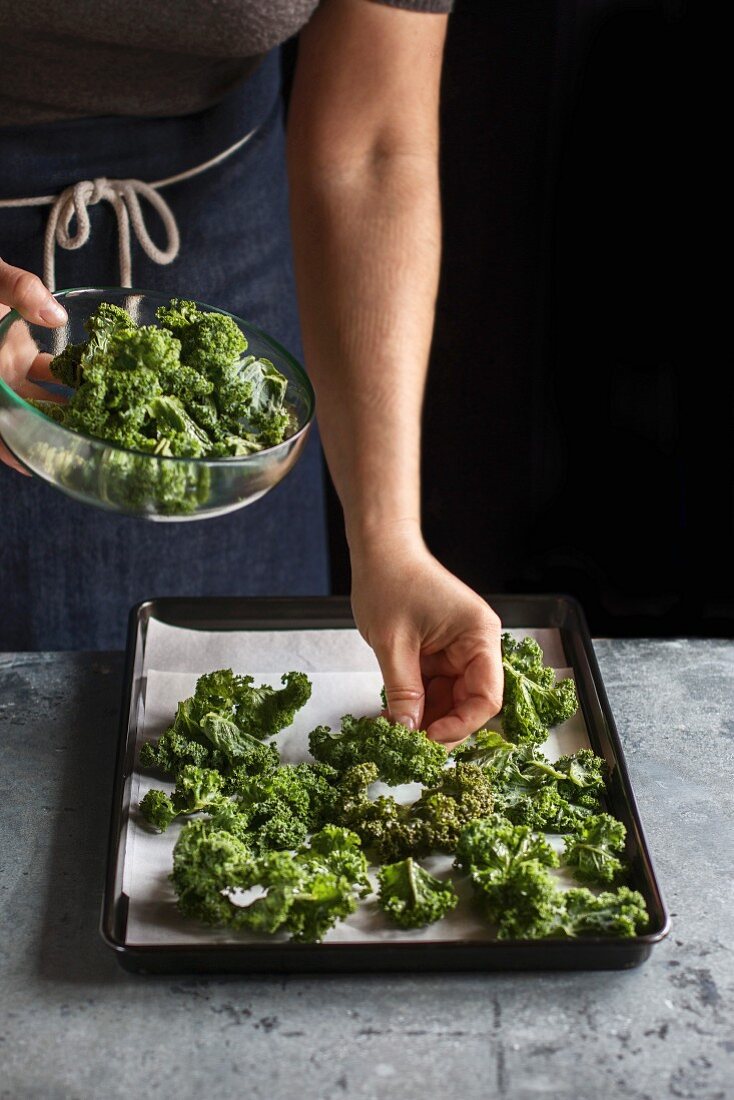 Kale-Chips zubereiten: Grünkohlblätter zum Backen auf Ofenblech legen