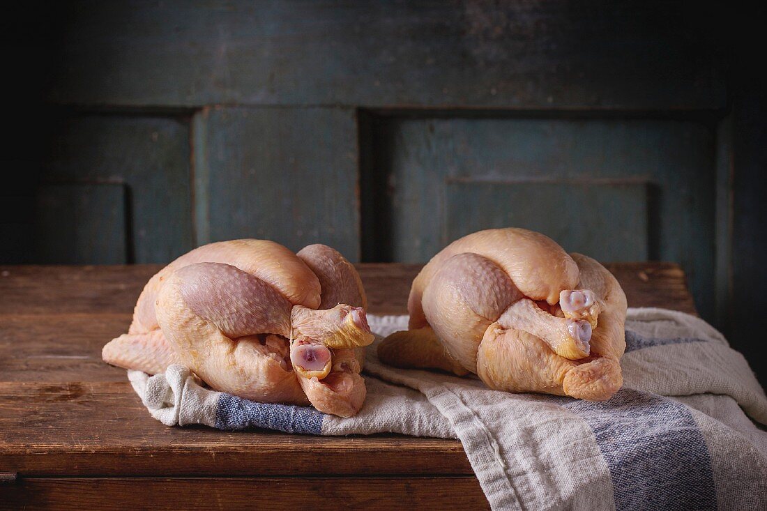 Two Raw mini Chicken on kitchen towel over old wooden table