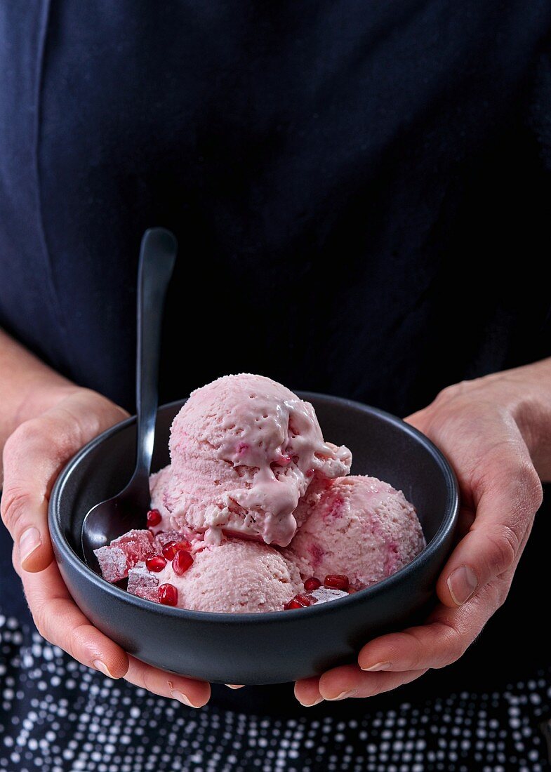 Pomegranate ice cream in a black bowl
