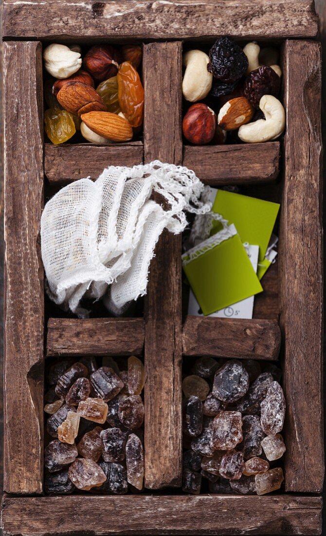 Tea bags, nuts, raisins, brown sugar in wooden box