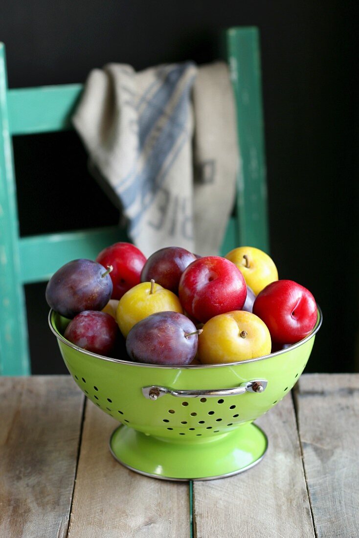 Different kinds of plum in enamel colander