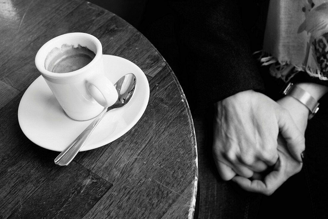 Händchen haltendes Paar mit Espresso in Pariser Café (schwarz-weiss-Aufnahme)