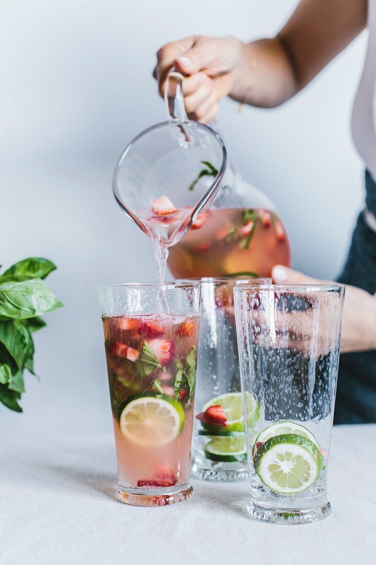 A woman is pouring some limeade into empty glasses