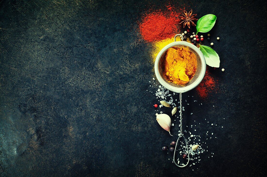 Herbs and spices selection (turmeric, paprika, basil, salt, papper) on dark rustic background