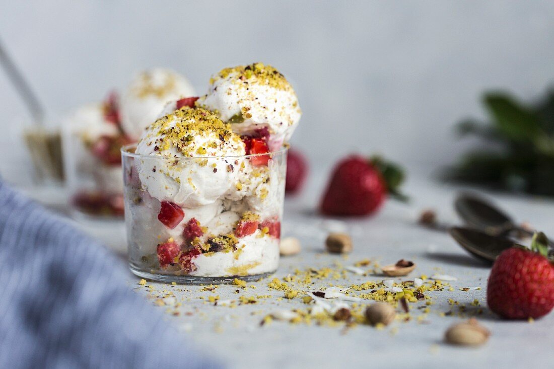 A couple scoops of coconut milk and cashew ice cream topped off with strawberries and pistachio crumbs