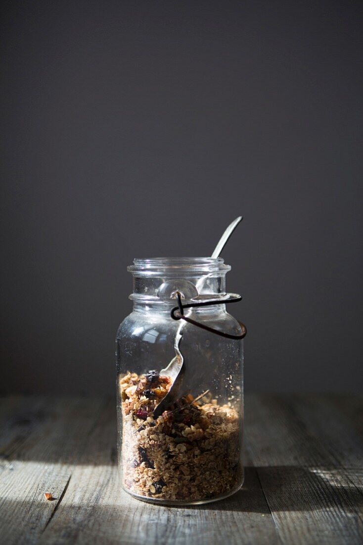 Jar of Homemade Granola with Nuts, Seeds Raisins and Cranberries with Spoon