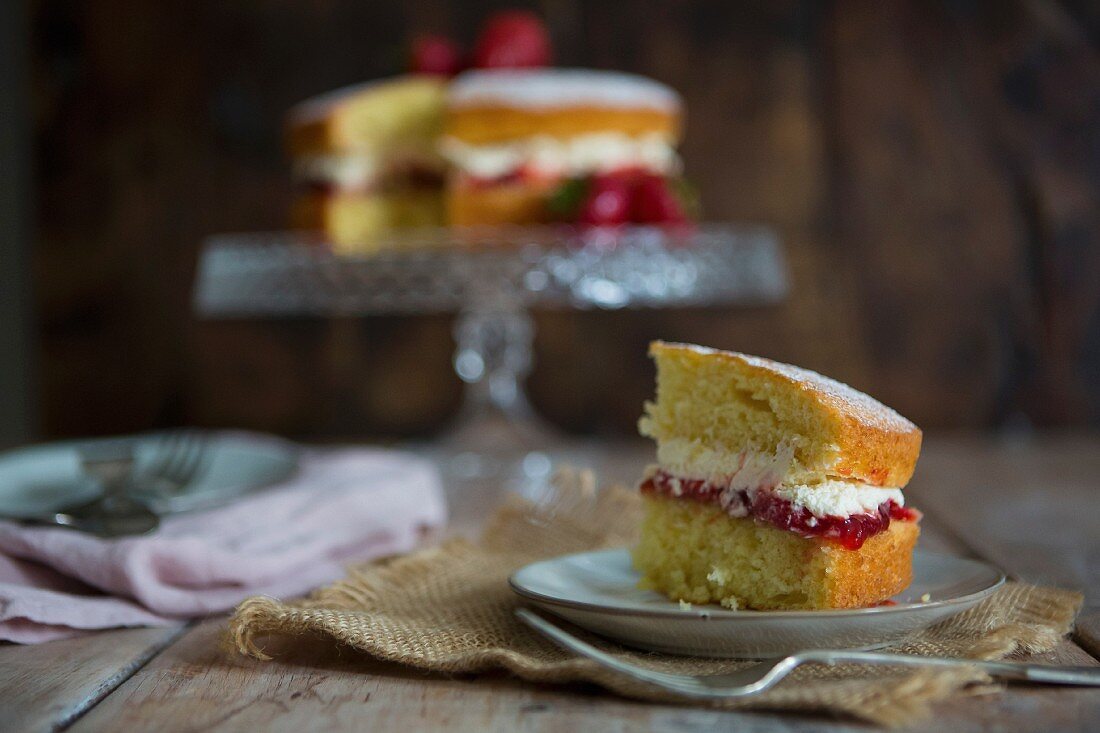 Ein Stück Victoria Sponge Cake mit Erdbeeren auf Teller (England)