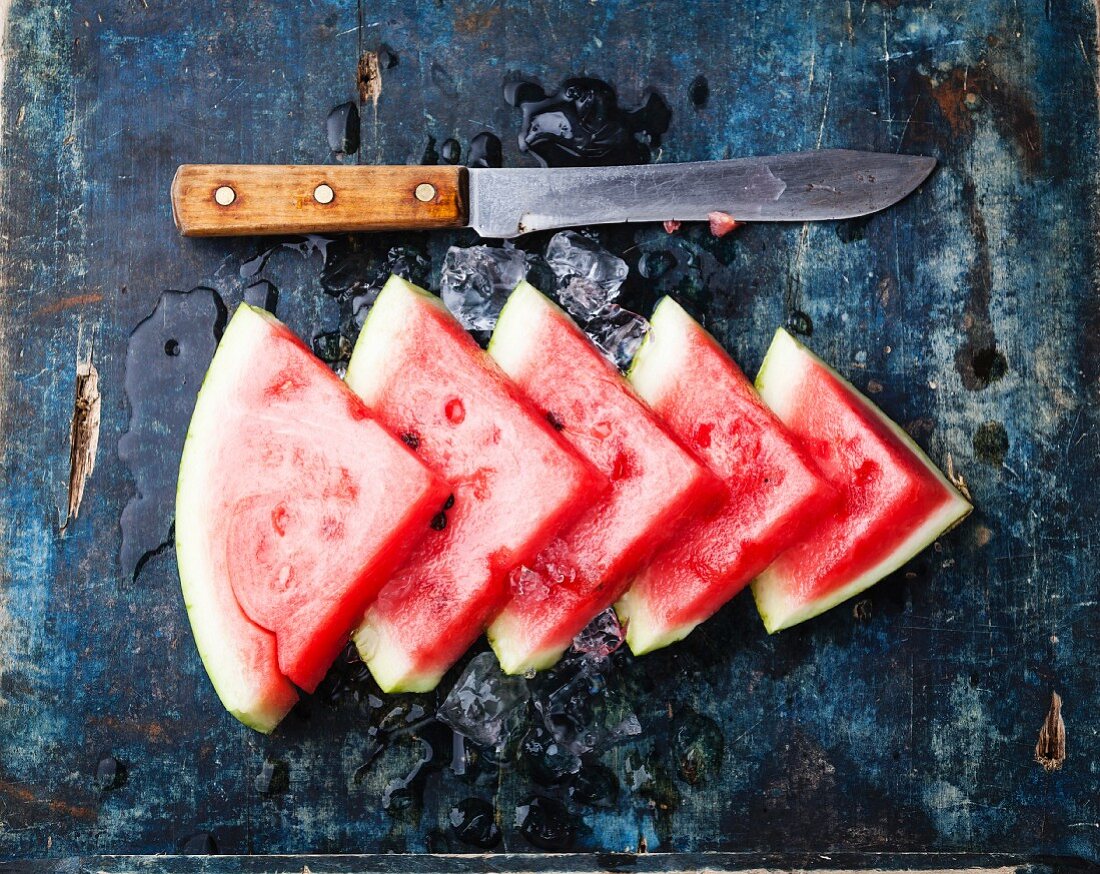 Wassermelonenscheiben mit Eiswürfeln auf blauem Hintergrund