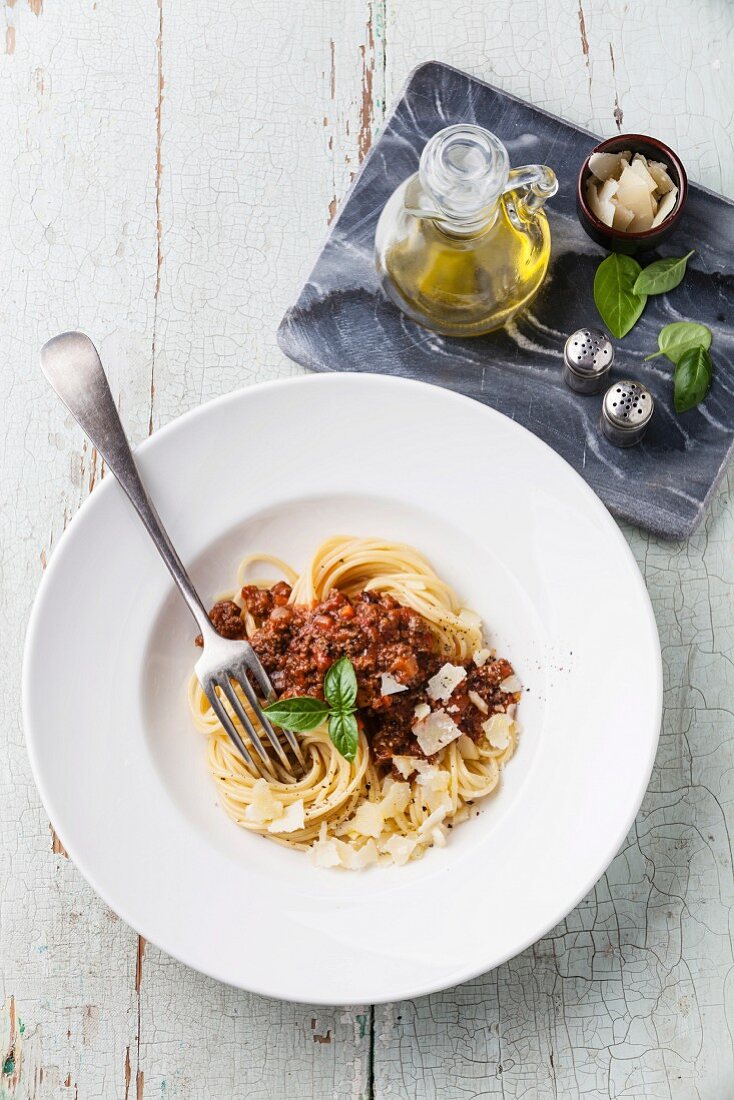 Spaghetti Bolognese in weißem Teller auf blauem Holzuntergrund