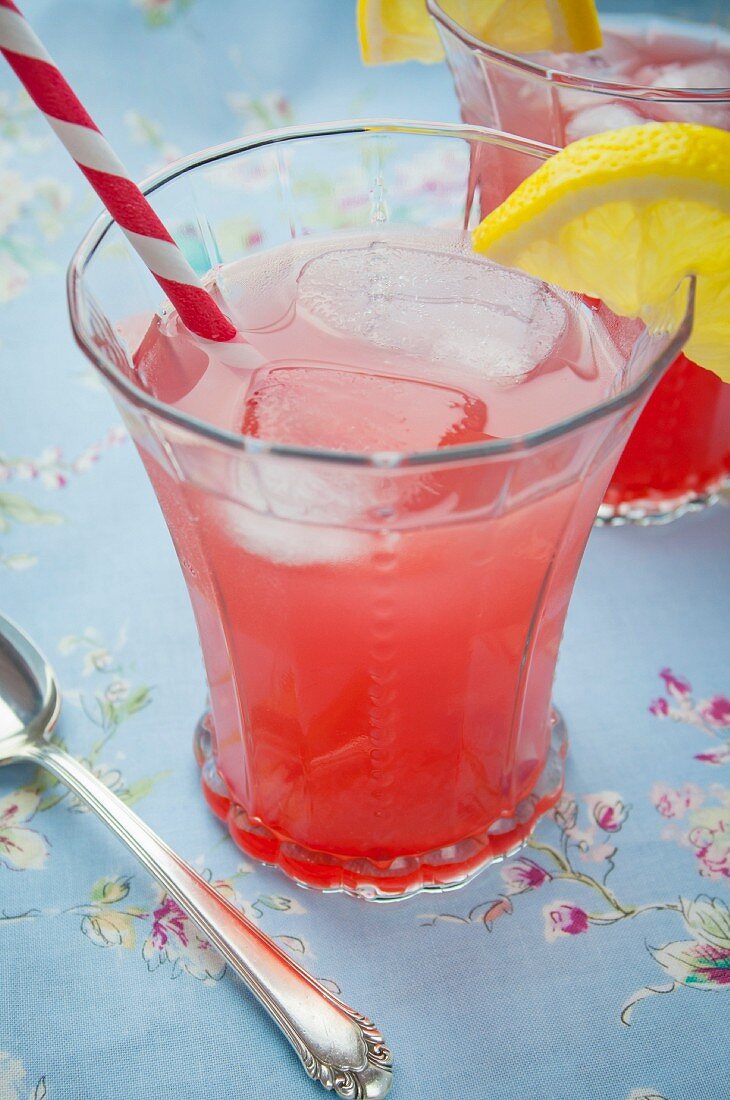Two Glasses of a Lemon Cherry Cocktail on Blue Table Cloth