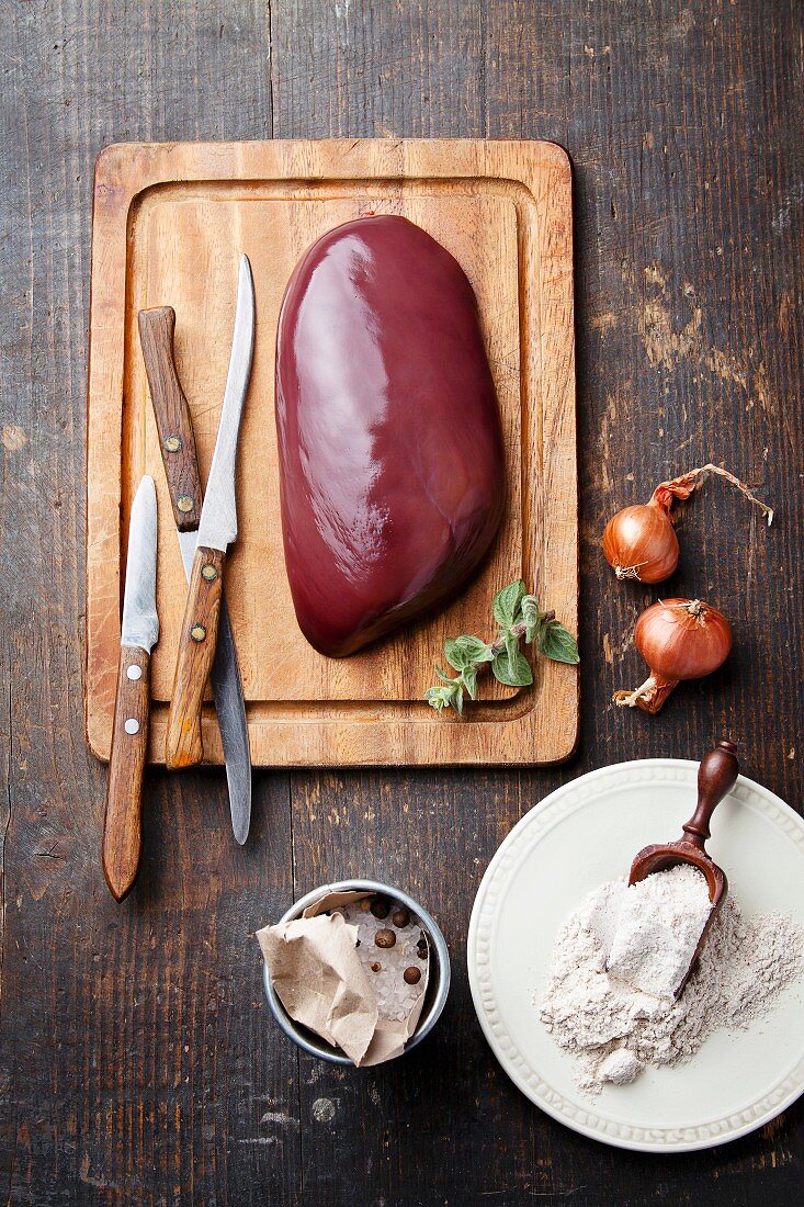Raw liver with ingredients on wooden textured table