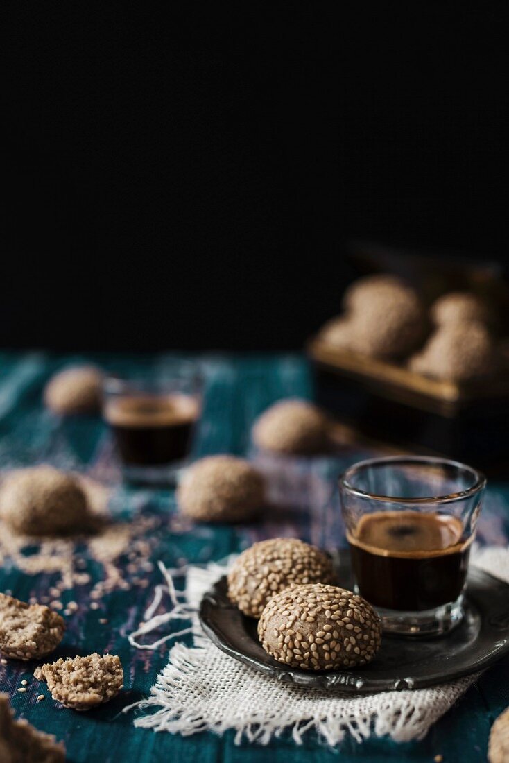 Tahini-Kekse zum Espresso im Glas auf Vintage-Holztisch