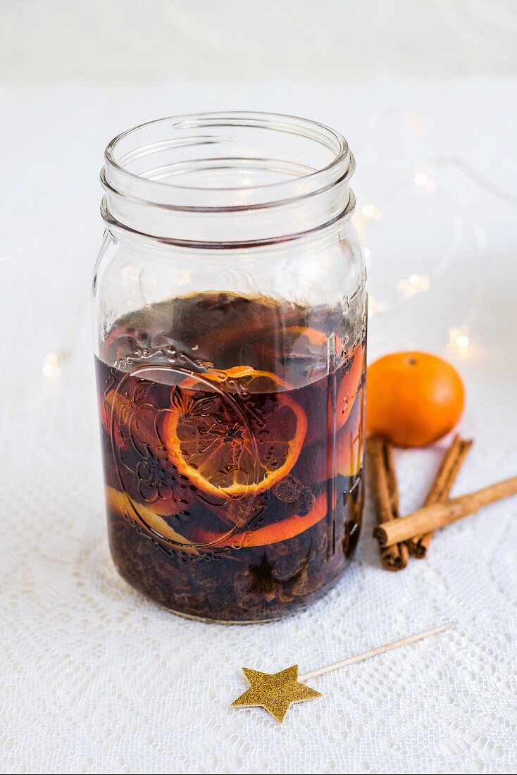 Homemade rum punch with clementines, raisins, cinnamon and lemon zest in a glass jar